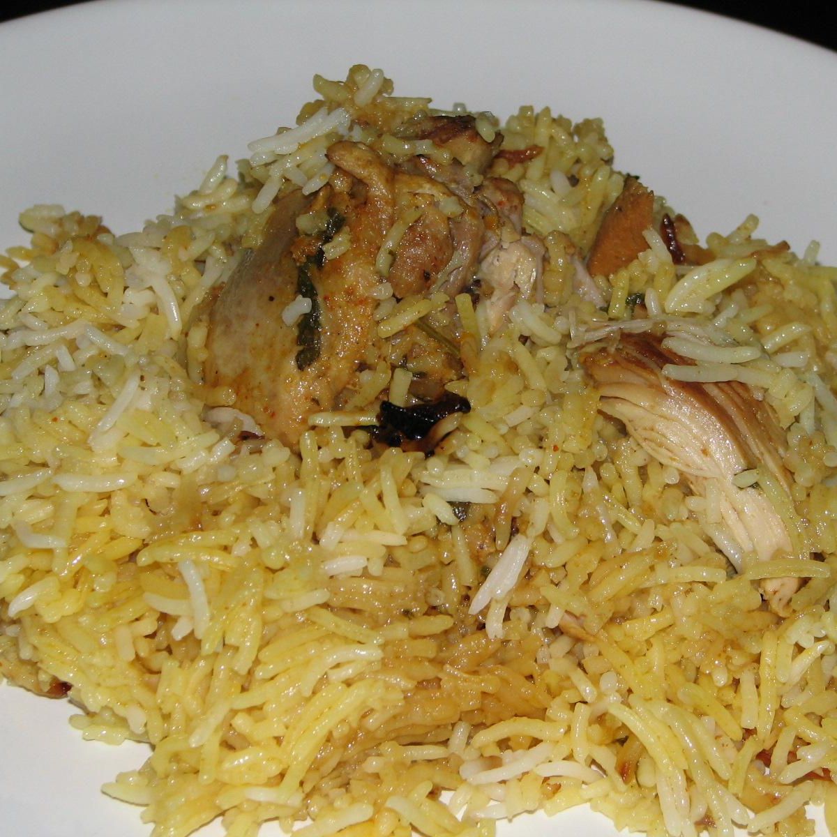 Traditional Hyderabadi dum biryani served on a steel thali, garnished with fried onions and herbs