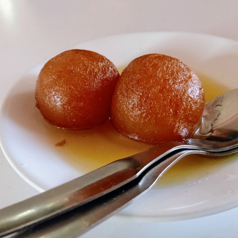 Warm gulab jamun served in syrup, a classic Indian dessert